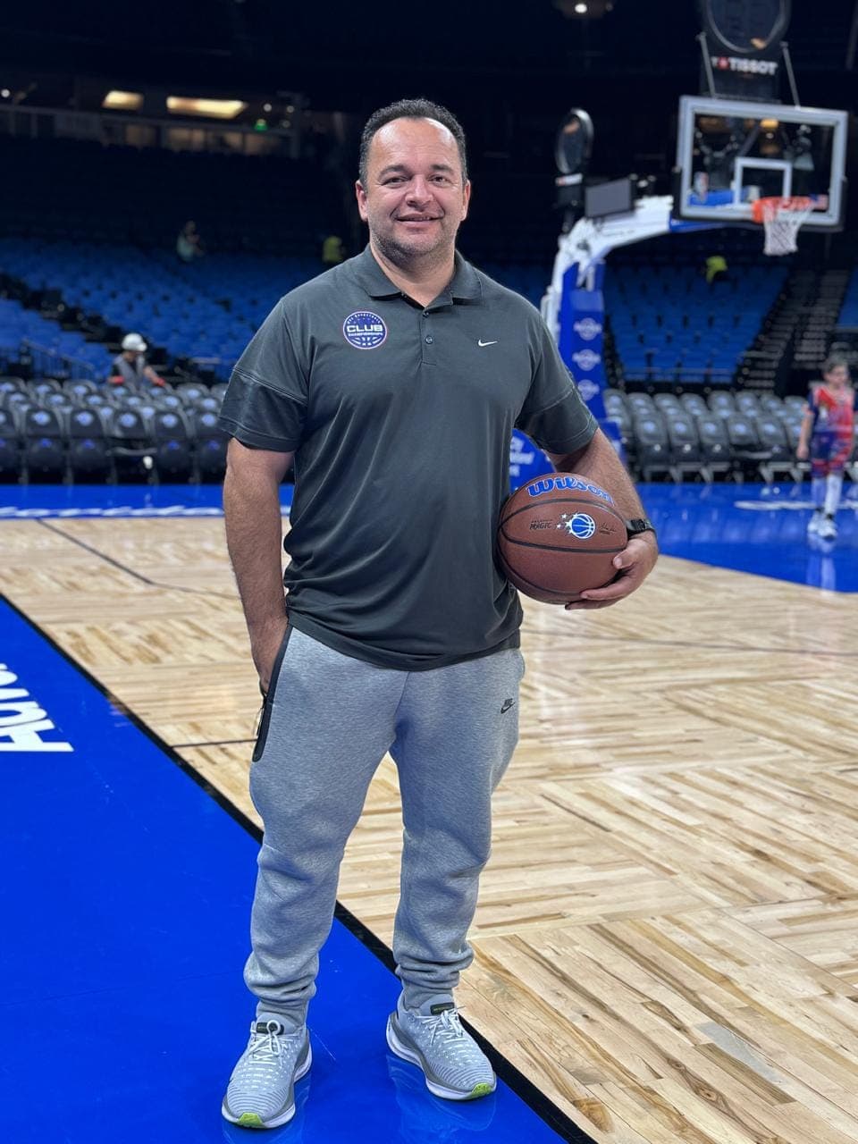 Carlos Oliveira na quadra do Orlando Magic segurando uma bola de basquete